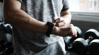 Spor salonunda akıllı saat kullanan yaşlı adam.