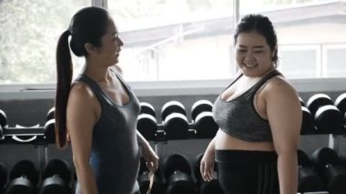 Genç ve cüsseli bir kadın kalçasını ve belini ölçmeye çalışan arkadaşına gülüyor. Asyalı kadın, fitness yaşam tarzı. 