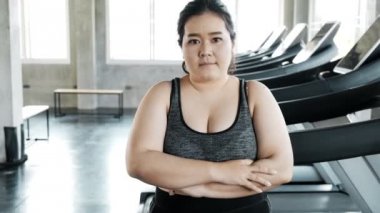 Genç şişman Asyalı kadın portresi. Arka planda jimnastik salonu var. Otantik Fitness yaşam tarzı konsepti.