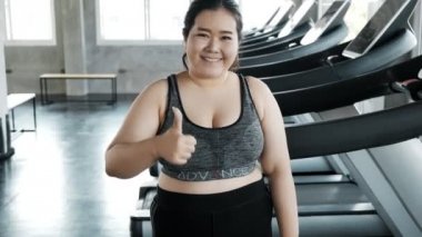 Genç şişman Asyalı kadın portresi. Arka planda jimnastik salonu var. Otantik Fitness yaşam tarzı konsepti.