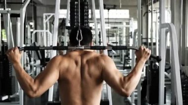 Genç bir adam spor salonunda aşağı çekme makinesi kullanıyor. Fitness yaşam tarzı.