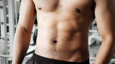 Genç Asyalı adam spor salonunda kaslarını gösteriyor. Ön çekim..