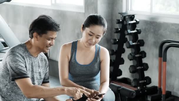 Asiático Senior Hombre Mujer Sentado Juntos Gimnasio Mirando Teléfono — Vídeo de stock