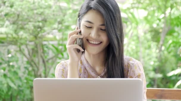 年轻迷人的亚洲女人打电话给她的顾客 看着自家花园的笔记本电脑 背景是绿树 近距离拍摄 千年商业妇女生活方式概念 — 图库视频影像