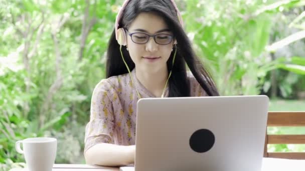 年轻迷人的亚裔女学生在户外的笔记本电脑上学习 背景是绿树成荫 千年教育生活方式概念 — 图库视频影像