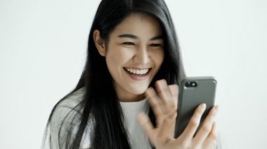 Genç, güzel Asyalı bir kadın arkadaşlarıyla görüntülü konuşma yapmak için cep telefonu kullanıyor. Mutlu bir ruh hali. Milenyum yaşam tarzı konsepti.