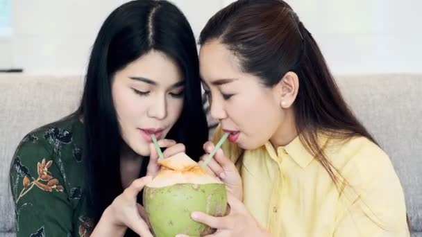 若い美しいアジアの女性はソファの上で彼女の母親とココナッツジュースを飲んで 一緒に飲む 若い女性関係の概念 — ストック動画