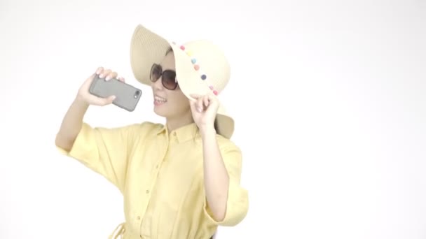 年轻美丽的亚洲女人 戴着夏帽 拿着手机唱歌 用白色背景的相机拍照 假日生活方式概念 — 图库视频影像