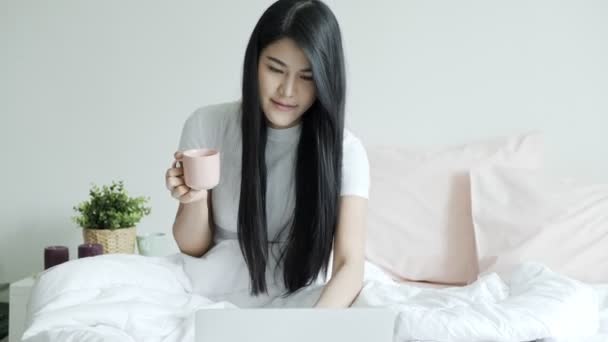 Young Beautiful Asian Woman Sitting Bed Holding Cup Coffee Typing — Stock Video