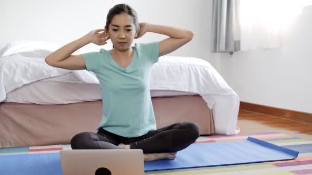 若い美しいアジアの女性は 寝室でラップトップを使用してインターネットからヨガを学ぼうとしています インターネットの概念からの自己学習 — ストック動画