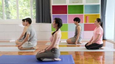 Yoga sınıfına katılan, oturmuş, dinlendirici bir grup genç ve üst düzey Asyalı insan. Grup spor yaşam tarzı.