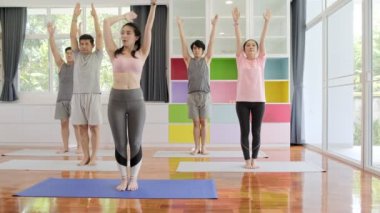 Yoga sınıfına katılan genç ve üst düzey Asyalı bir grup, ayağa kalkmave omuz germe. Grup spor yaşam tarzı.