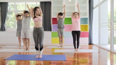 Yoga sınıfına katılan genç ve üst düzey Asyalı bir grup, ayağa kalkmave kollarını germe. Grup spor yaşam tarzı.