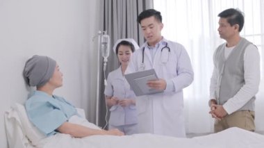 Asyalı yaşlı kadın doktor, hemşire ve eşi onun hastalık hakkında konuşurken yatakta yatıyordu.