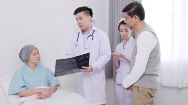Asyalı yaşlı kadın doktor, hemşire ve eşi xray film ile hastalığı hakkında konuşurken yatakta yatıyordu.