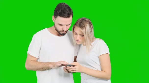 緑色の画面でモバイル アプリケーションを使用して方向性を見つけるしようとしている若いカップル 白い男性と女性 クロマキー — ストック動画