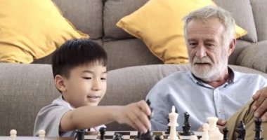 Büyükbabam evinde torunuyla satranç oynuyor.