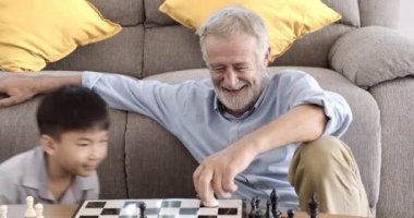 Büyükbabam evinde torunuyla satranç oynuyor.