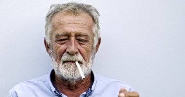 Yaşlı Asyalı adam beyaz arka planda sigara içiyor