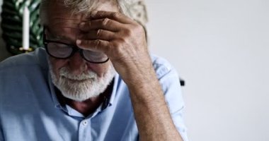 Yaşlı Asyalı adam bir şey okuyor ve düşünüyor.