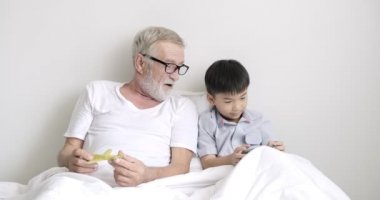 Genç asyalı çocuk klinikte dedesi ile cep telefonu kullanıyor