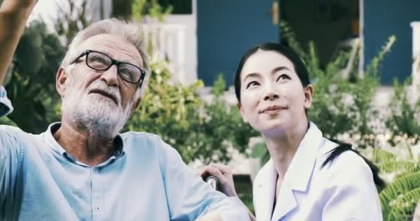 Ungsjuksköterska Pratar Med Äldre Funktionshindrade Man Rullstol Trädgården — Stockvideo