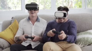 Kafkas eşcinsel çift evde joystics video oyunu oynuyor ve sanal gerçeklik gözlük giyiyor 
