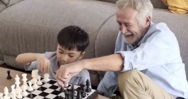 Büyükbabam evinde torunuyla satranç oynuyor.