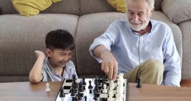 Büyükbabam evinde torunuyla satranç oynuyor.