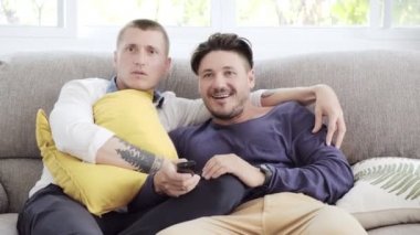 Kafkas eşcinsel çift evde kanepeye yatarken ve Tv izliyor 