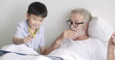 Yaşlı olgun adam oyuncak uçaklar ile oynarken ve klinikte torunu ile kitap okuma