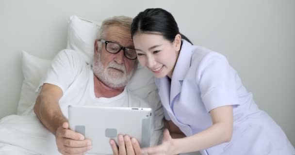Oude Aziatische Man Toont Iets Tablet Aan Jonge Verpleegster — Stockvideo