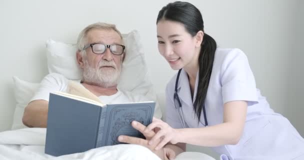 Velho Homem Maduro Está Mostrando Livro Para Jovem Enfermeira — Vídeo de Stock