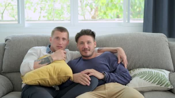 白人同性恋夫妇躺在家里的桌子上看电视 — 图库视频影像