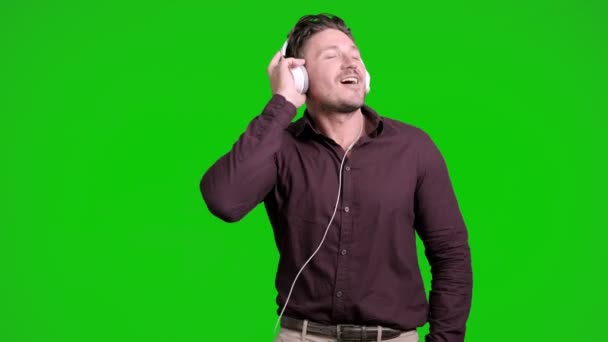 Kaukasier Hört Musik Über Kopfhörer Und Tanzt Auf Grünem Hintergrund — Stockvideo
