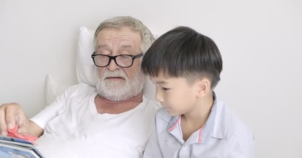 老成熟的人玩玩具飞机和阅读书与他的孙子在诊所 — 图库视频影像