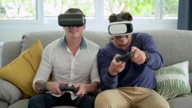 Kafkas eşcinsel çift evde joystics video oyunu oynuyor ve sanal gerçeklik gözlük giyiyor 