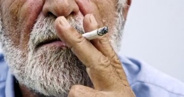 Yaşlı Asyalı adam beyaz arka planda sigara içiyor