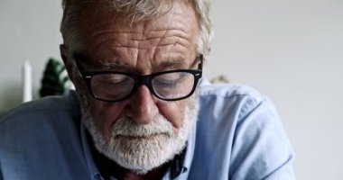 Yaşlı Asyalı adam bir şey okuyor ve düşünüyor.