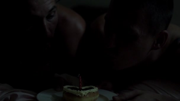 caucasien gay couple est couché sur lit avec gâteau dans coeur forme sur assiette 