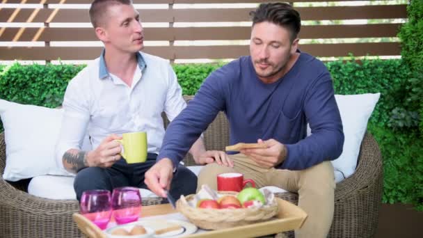 高加索同性恋夫妇是在花园里吃早餐 — 图库视频影像