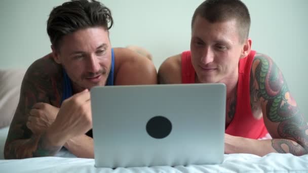 白人同性恋夫妇躺在床上 在家里看笔记本电脑的东西 — 图库视频影像