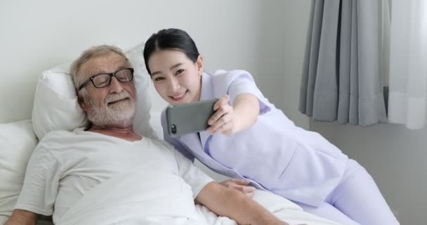 老亚洲男子正在做自拍与年轻的护士在手机 — 图库视频影像