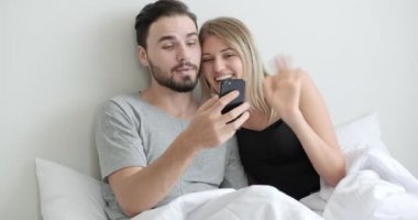 Canlı yayında cep telefonu kullanan çift, yatakta arkadaşlarıyla görüntülü konuşma, el dokuma. Beyaz erkek ve kadın..