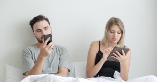 Ζευγάρι Στο Κρεβάτι Χρησιμοποιώντας Κινητό Τηλέφωνο Και Tablet Μαζί Διάθεση — Αρχείο Βίντεο