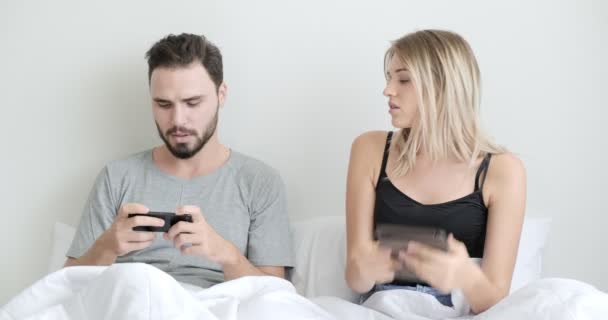 Pareja Cama Usando Teléfono Móvil Tableta Juntos Mujer Aburrida Hombre — Vídeo de stock