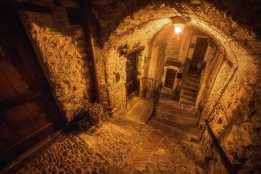 Subterranean street in the night and cozy countryard in the old town of Dolceacqua, Liguria region, Italy clipart