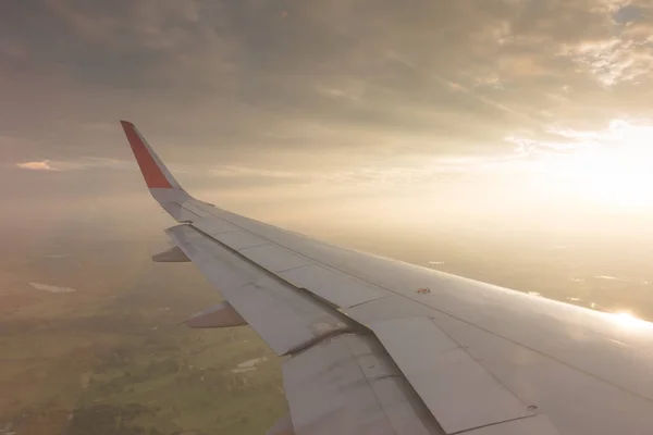 Flügel eines Flugzeugs, das bei Sonnenuntergang über den Wolken fliegt . — Stockfoto