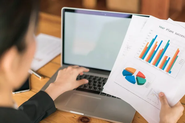 Femme d'affaires main avec des tableaux financiers et ordinateur portable sur la table — Photo