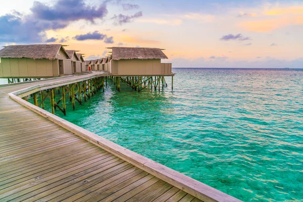 Hermosas villas de agua en la isla tropical de Maldivas al atardecer — Foto de Stock